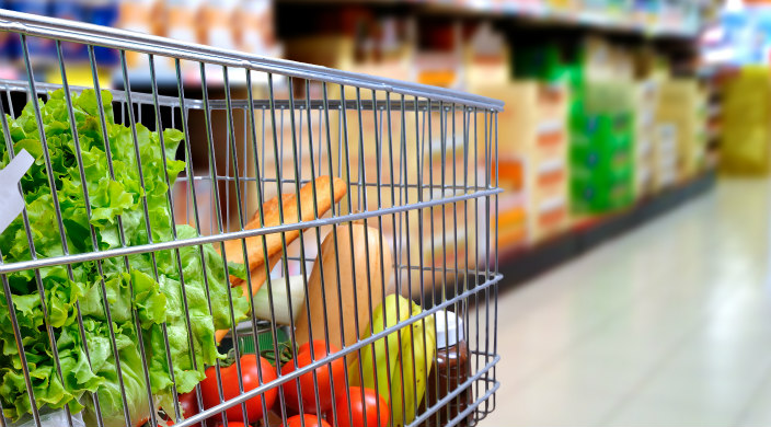 Side view of grocery cart containing produce, bread, and several other items
